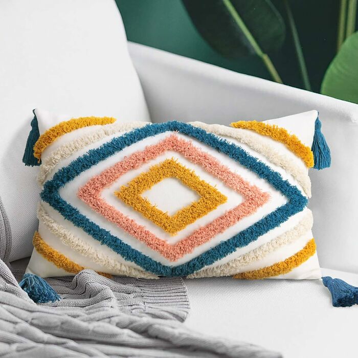 Colorful geometric cushion on a white sofa, showcasing a stylish spring find with tassels and textured patterns.