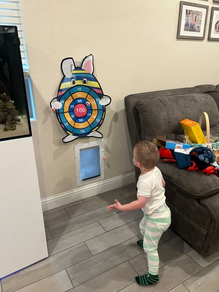 Toddler playing Easter-themed dart game indoors, aiming for fun new holiday activity.