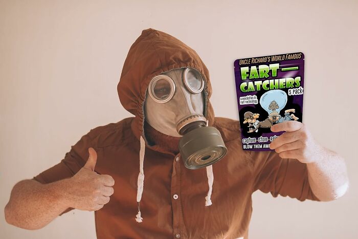 Person in gas mask holding "Fart Catchers" pack, giving thumbs up, illustrating toilet humour concept.