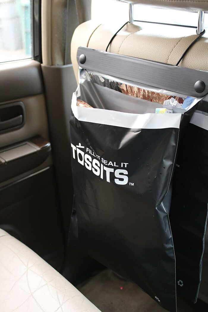 Car organizer bag on a seat, designed to reduce adult chaos with easy waste storage.