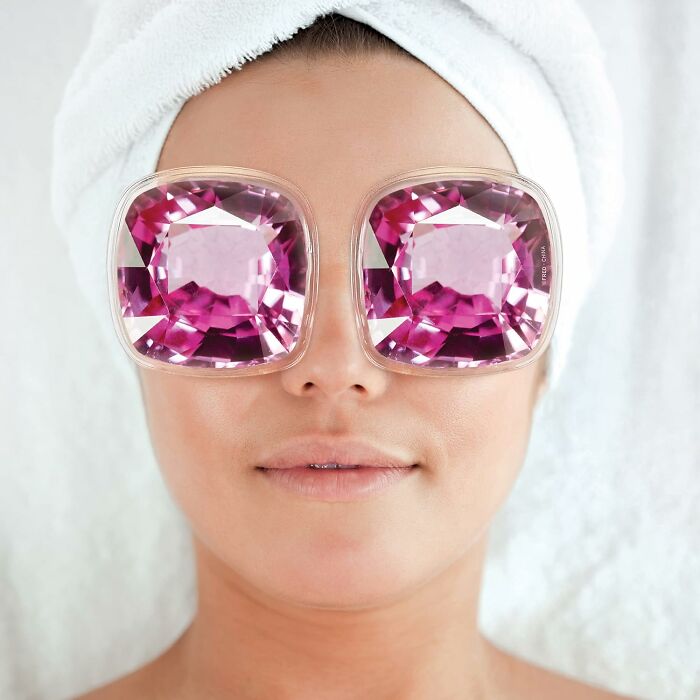 Person wearing Genuine Fred glasses with large pink gemstone design, towel wrapped around head, relaxed expression.