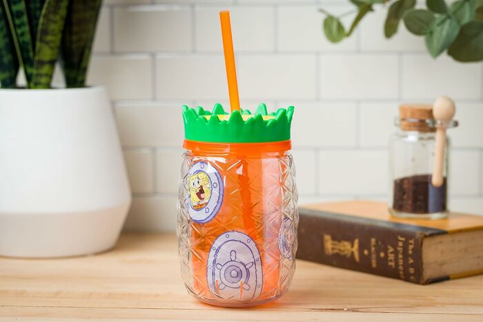 Pineapple-themed cup featuring a cartoon character sticker, ideal for fandom enthusiasts.