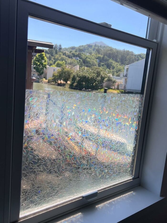Frosted window with rainbow pattern, showcasing a simple DIY home project with a scenic view outside.
