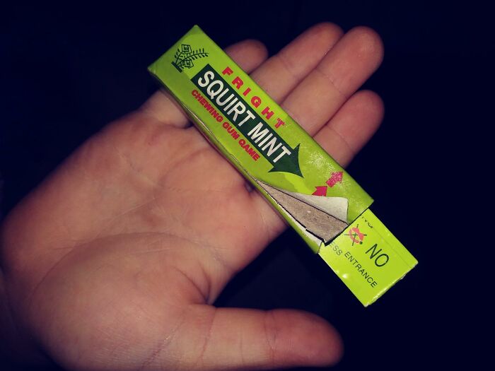 Hand holding a prank chewing gum pack labeled "Fright Squirt Mint" for April Fools fun.