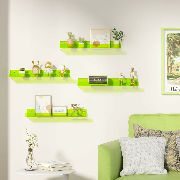 Bright green shelves with 80s treasures and decor on a cream wall above a green sofa.