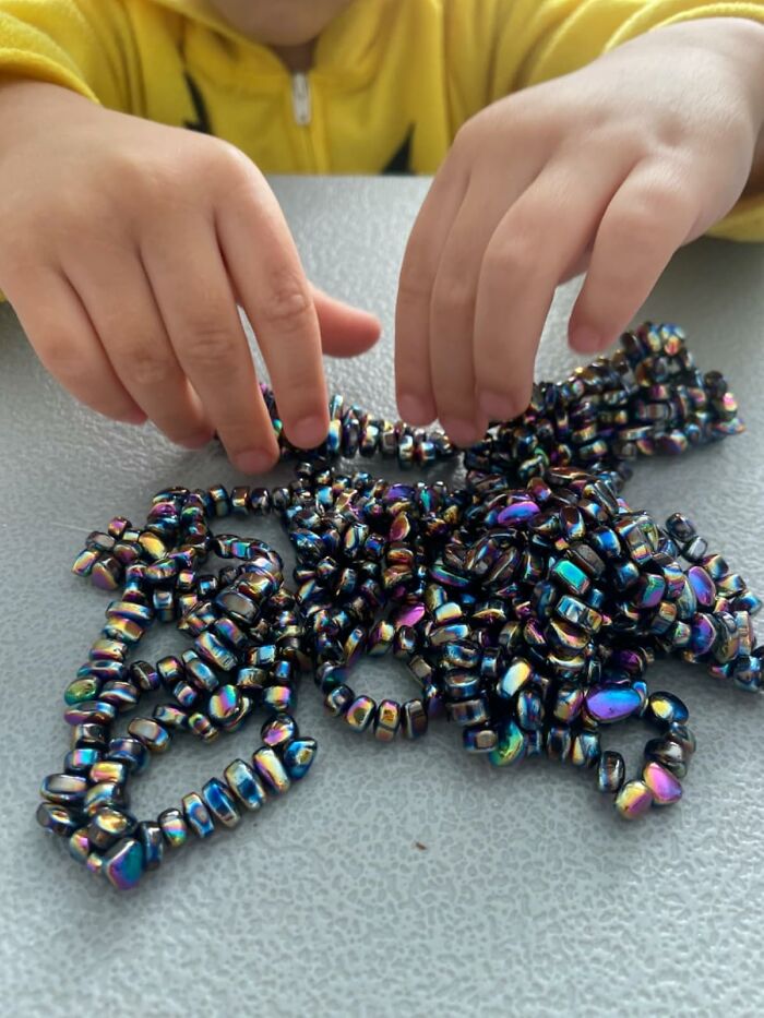 Child playing with vibrant beads, showcasing bargain spring discounts.