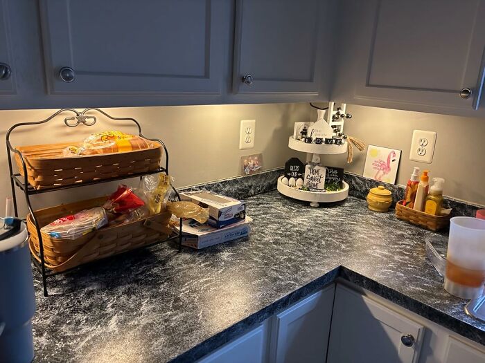 DIY home project: organized kitchen countertop with baskets and decor under cabinet lighting.