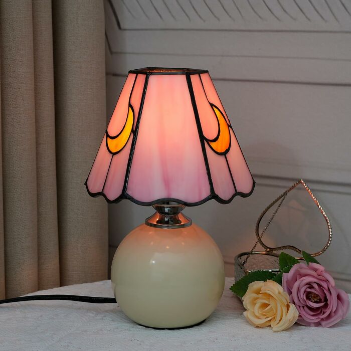 80s style lamp with pink stained glass shade and yellow crescent details on a round base, evokes nostalgic memories.