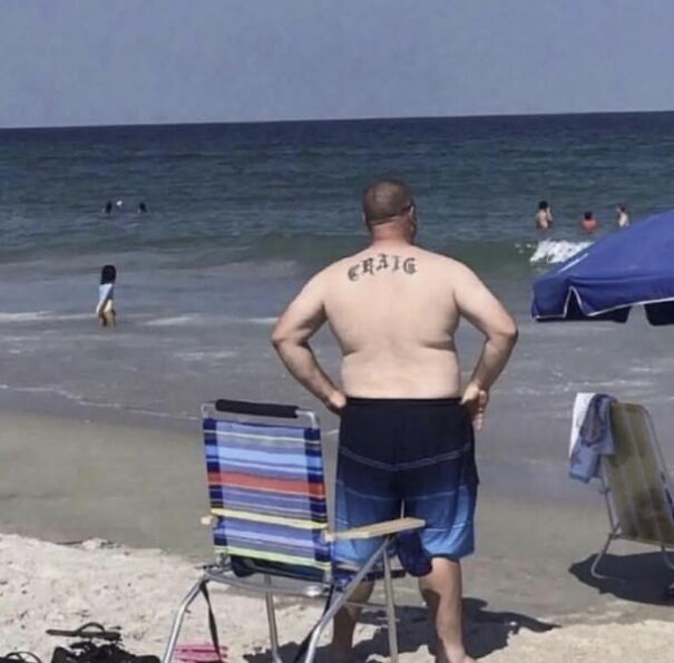 Man with "Craig" tattoo on his back standing by the beach, showcasing Scottish humor.