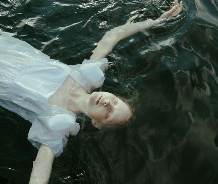 Person in a white dress floating peacefully in water, highlighting sudden dizziness awareness.