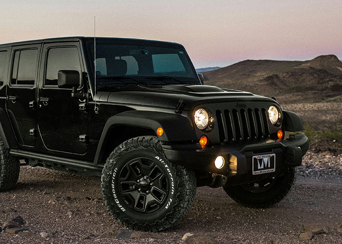 Black Jeep parked in a desert landscape at dusk, highlighting adventure and memorable road trips.
