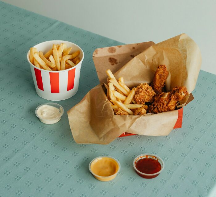Fast food mix of fried chicken and fries with dipping sauces on a table.