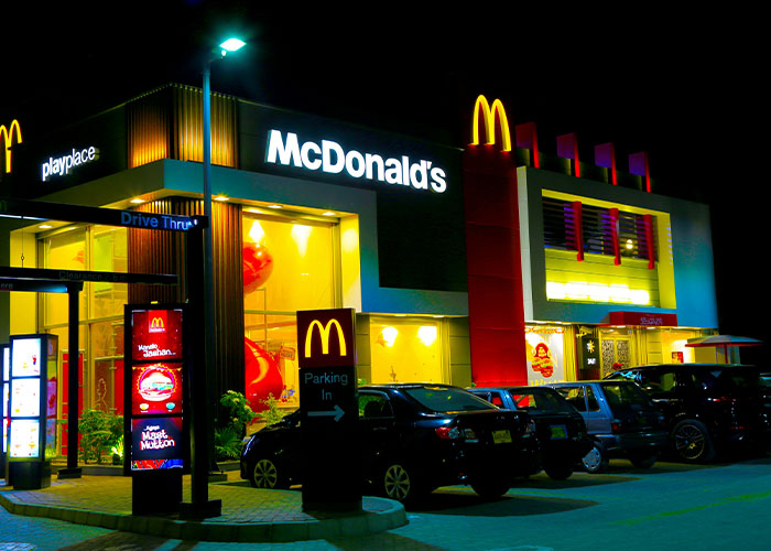 Exterior of a McDonald's restaurant at night, with cars parked outside, relating to brand boycotting.