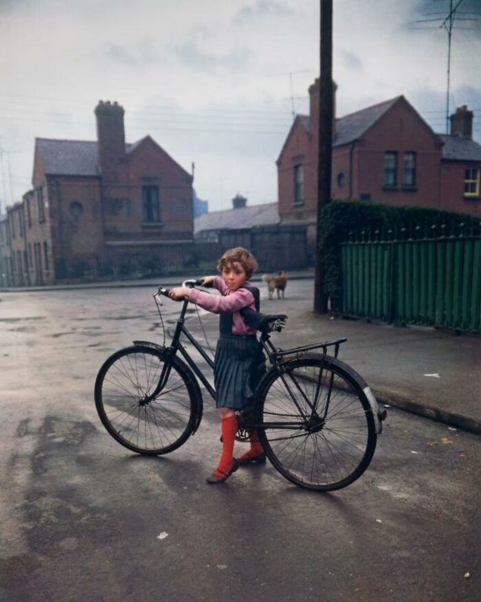 Child with a bicycle on a street, capturing an unexpected moment with a dog in the background, showcasing perfectly timed street photography.