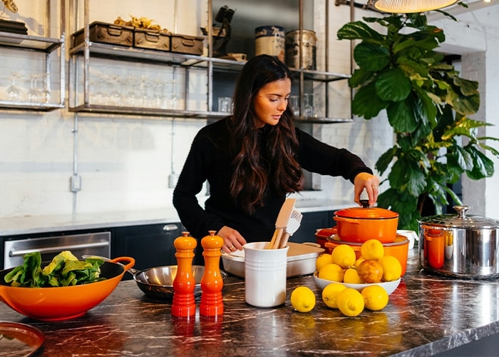 Woman cooking in a modern kitchen with fresh ingredients on the counter, highlighting parenting mistakes concept.
