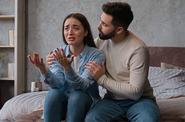 Woman upset about smelling, man consoling her on a bed. Woman upset about smelling, man consoling her on a bed.