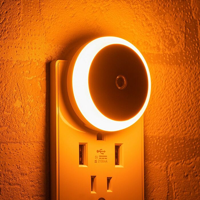 Night light plugged into a wall socket, emitting a warm glow on a textured surface. New finds in home lighting.