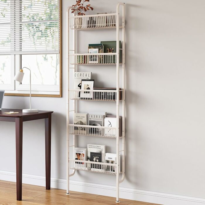Vertical storage shelf in a small room with books and decor for efficient living.