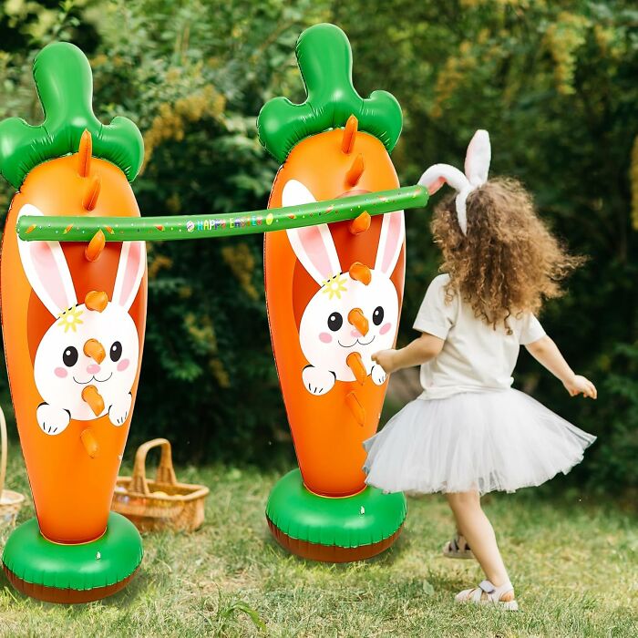 Child playing with inflatable bunny carrots, enjoying fun Easter activities outdoors.