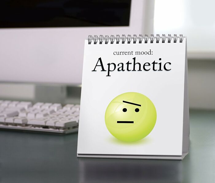 Desk calendar by Genuine Fred with an apathetic emoji on a workspace.