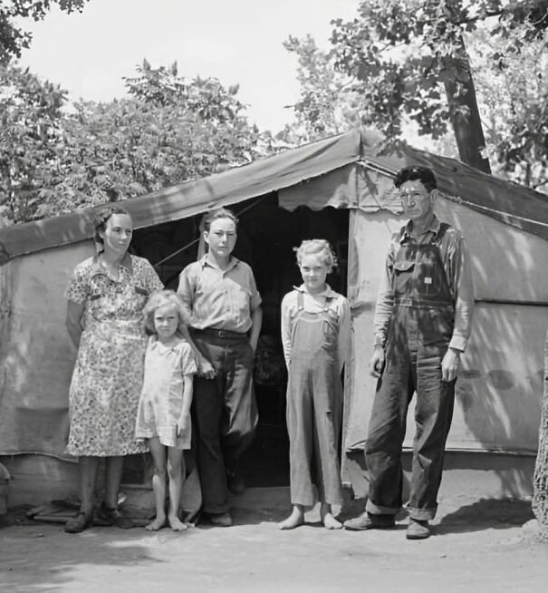 Historical photo of a family standing in front of a canvas tent, illustrating past perspectives.
