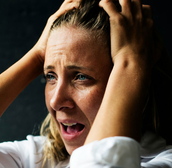 Woman looking stressed, holding her head, with focus on family pressure and parental role dynamics.
