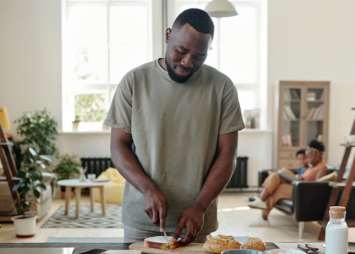 Man slicing bread in kitchen, embodying memorable dad moments.