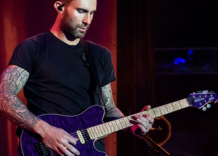 Musician playing guitar on stage, related to boycotting brands.