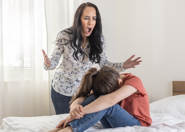 Mother yelling at daughter on a bed, illustrating parenting mistakes.