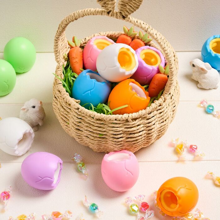 Easter basket with colorful plastic eggs and toy carrots, surrounded by small animal figures and candies.