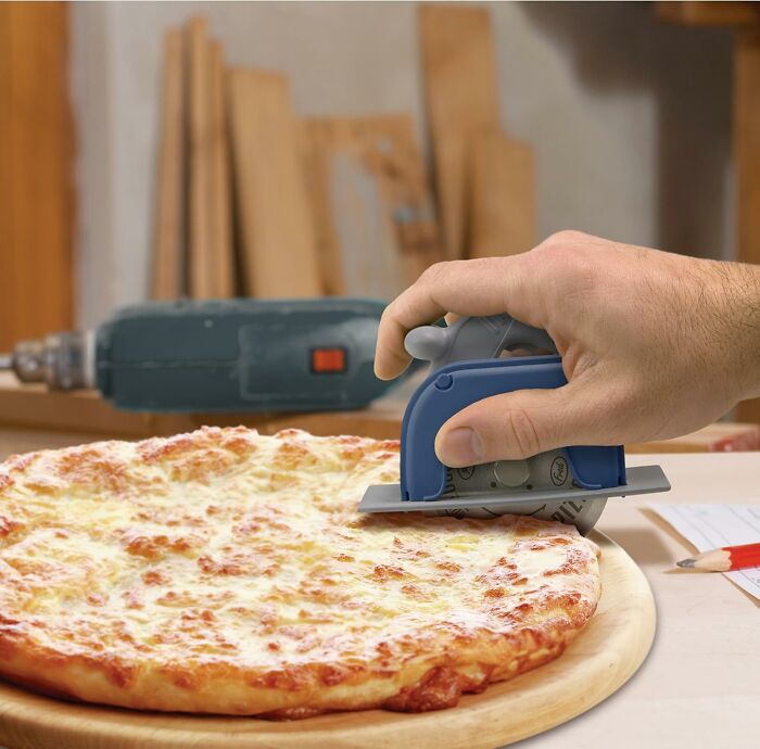 Hand using a pizza cutter shaped like a power tool on a cheese pizza, a kitchen game-changer.
