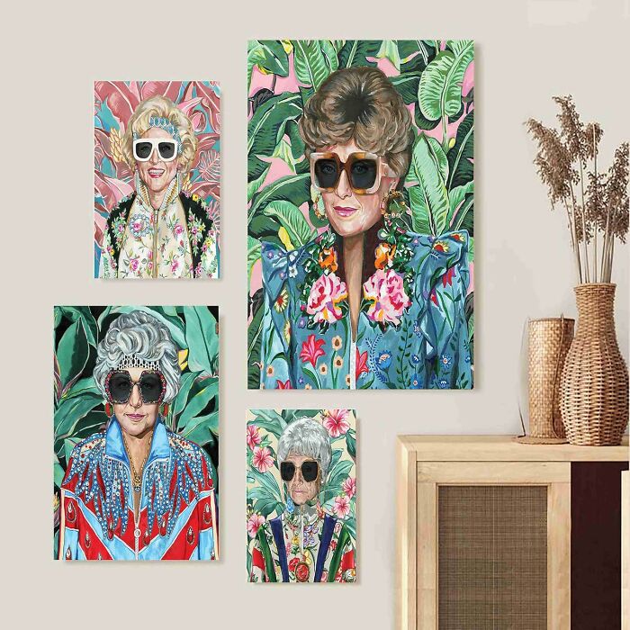 Colorful 80s-inspired portraits with sunglasses and floral backgrounds hanging on a beige wall near a wooden cabinet.