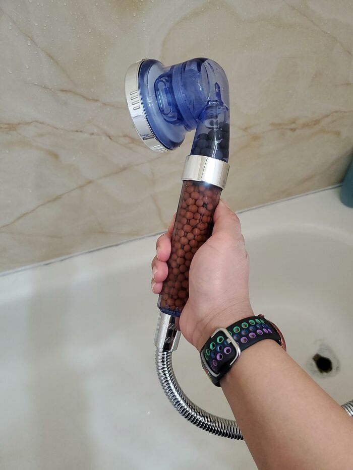 Innovative showerhead with mineral filter, held over a bathtub, showcasing one of the exciting new finds.