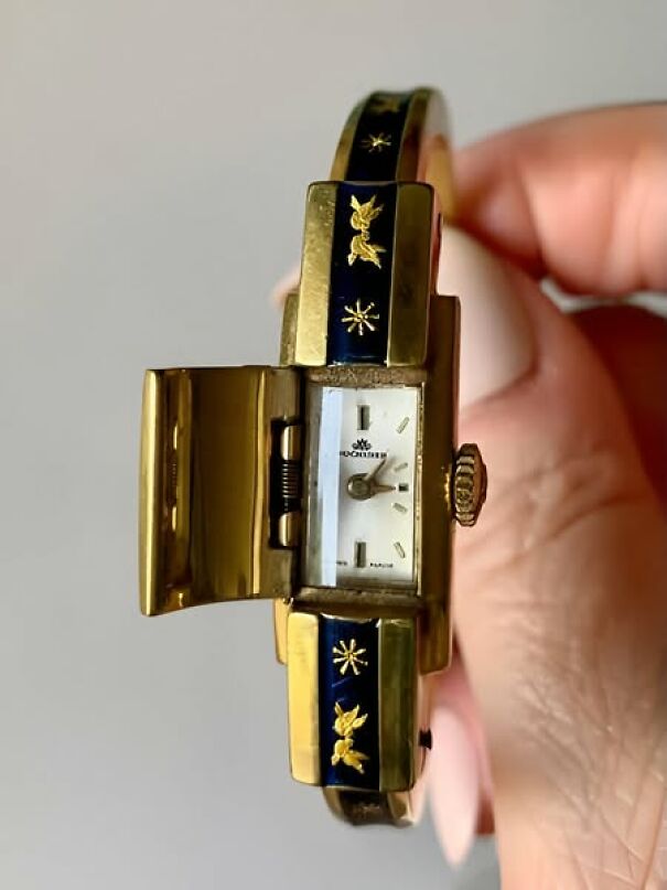 Unique thrift find: a vintage wristwatch hidden within a gold bracelet adorned with blue and gold designs.