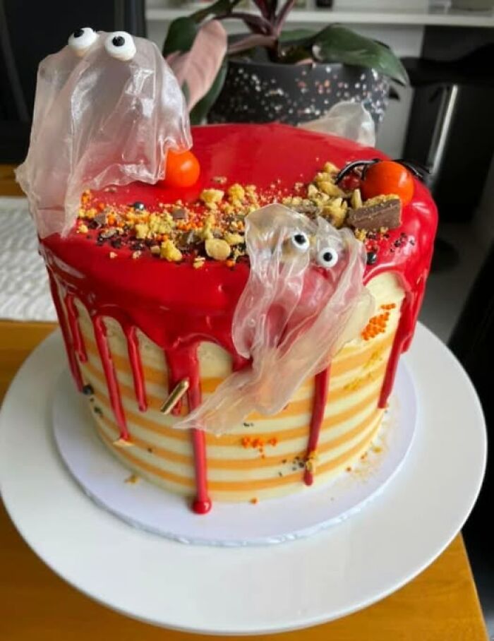 Cake with red icing, topped with candy eyes and plastic ghosts, showcasing a funny baking fail.