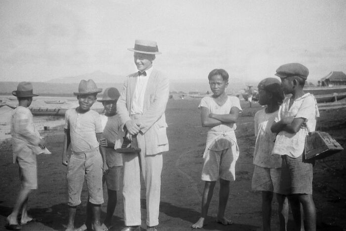 Group of people in vintage attire by the shore, showcasing rare photos of how the world has changed.