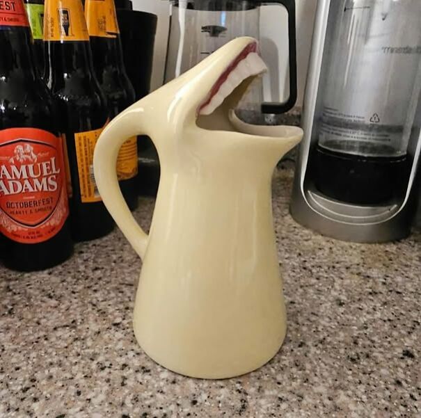 Strange shark-shaped jug found while thrifting, displayed on a kitchen counter near bottles.