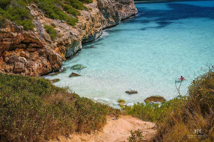 Crystal-clear waters and rocky cliffs at a stunning beach, inviting travelers to explore.