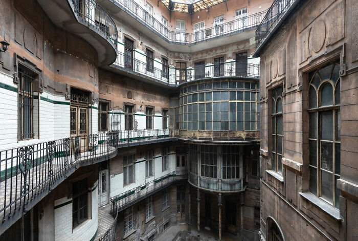 Abandoned places: interior of a deserted multi-story building with balconies and glass windows, creating an eerie atmosphere.
