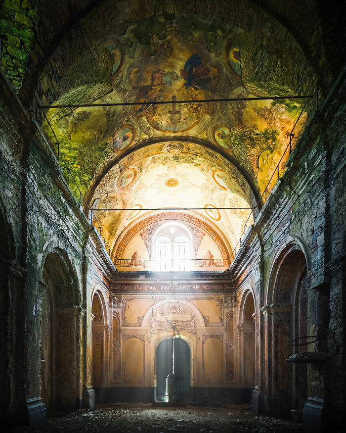 Abandoned place with ornate ceiling and sunlight filtering through a window, creating an eerie yet stunning atmosphere.