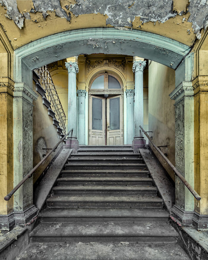 Abandoned place with worn stairs leading to a weathered door and peeling walls, creating an eerie atmosphere.