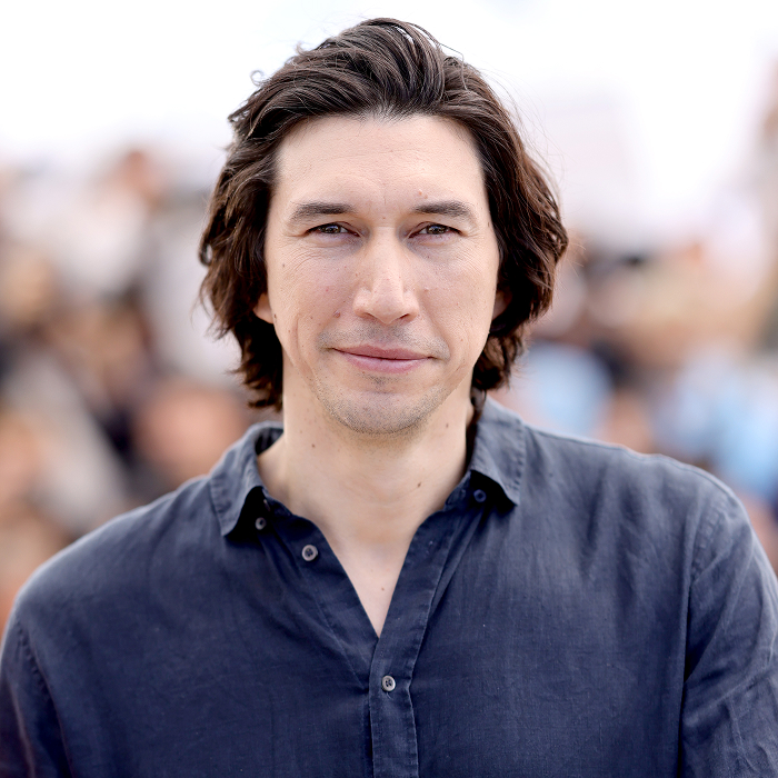 A celebrity in a casual blue shirt, outdoors, showcasing attractiveness in a natural setting.