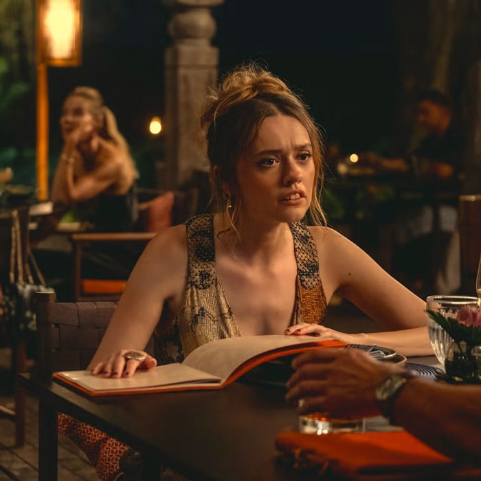 A person reading a menu at a restaurant table, engaged in conversation, with warm ambient lighting.