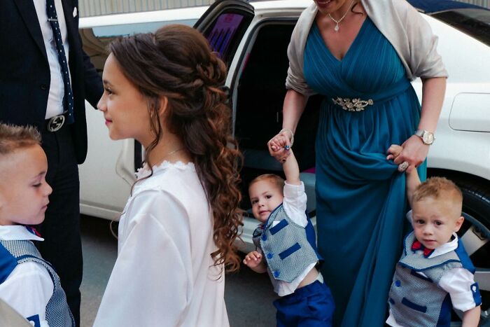 Street photo by Andrea Torrei of a woman and children dressed formally near a white car.