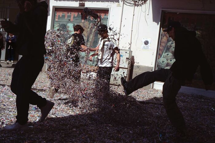 Street photo showing people playing with confetti, capturing lively street activity and candid moments.