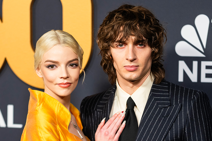 Anya Taylor-Joy & Malcolm McRae on the red carpet pose together, dressed in stylish formal attire.