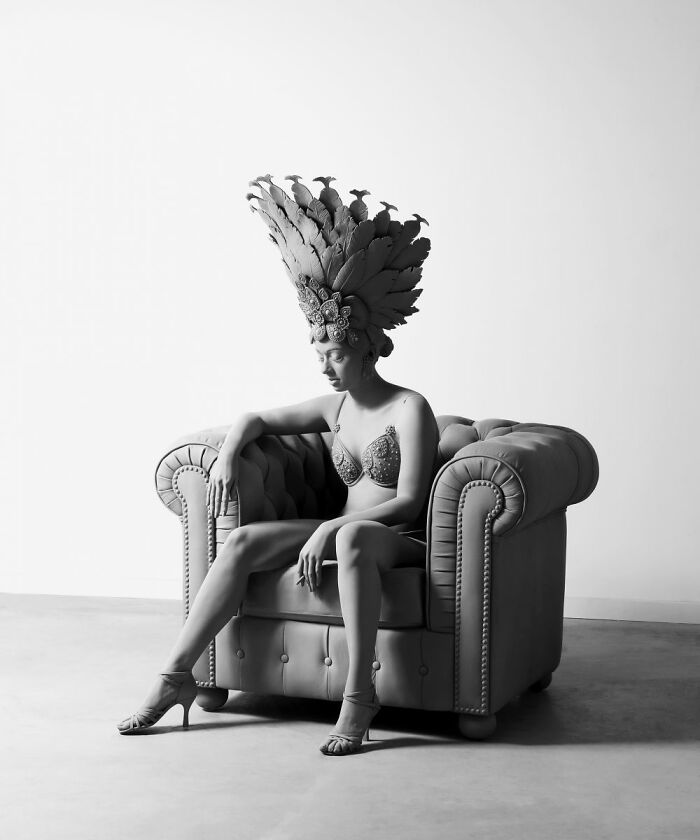 Monochrome sculpture by Hans Op De Beeck, depicting a woman seated in a chair with an elaborate headdress.