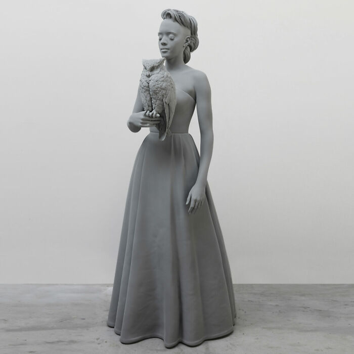 Monochrome sculpture by Hans Op De Beeck depicting a woman in a gown holding an owl, exuding a hauntingly still atmosphere.