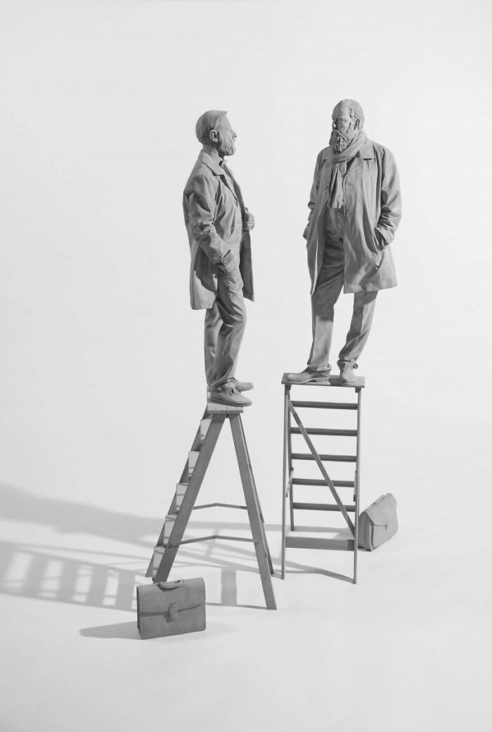 Monochrome sculptures by Hans Op de Beeck, featuring two figures on ladders in a minimalist setting.