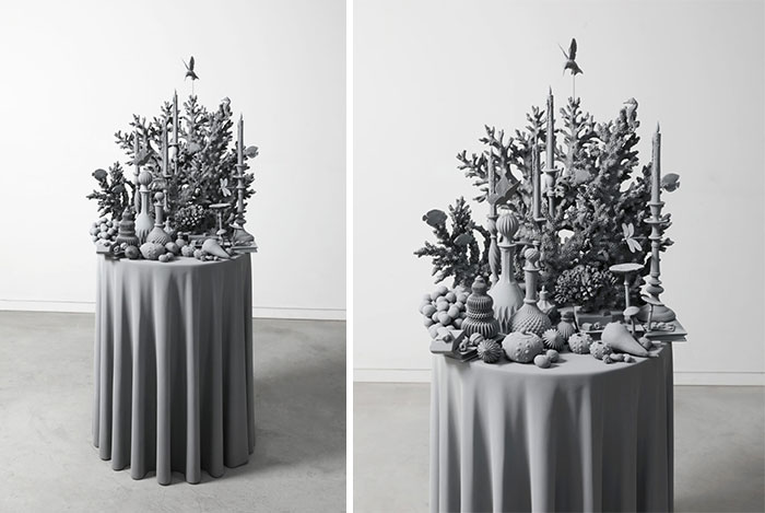 Monochrome sculpture by Hans Op De Beeck featuring intricate still life on a draped pedestal.